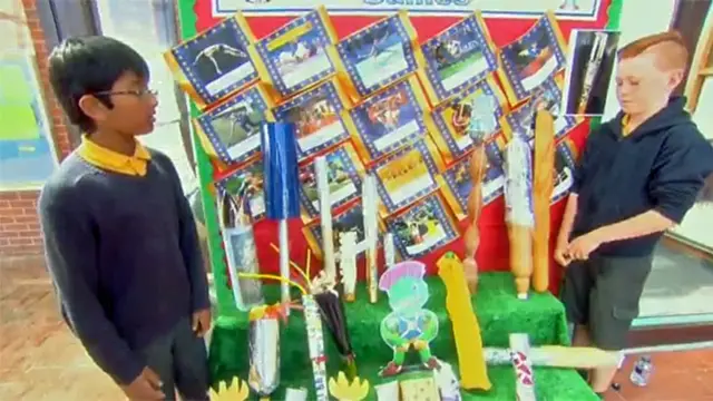 Two boys look at a variety of home made Queen's batons