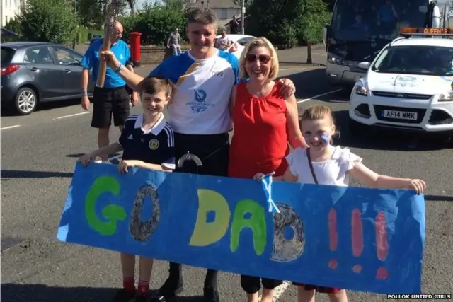 baton bearer with family and banner saying "go dad"