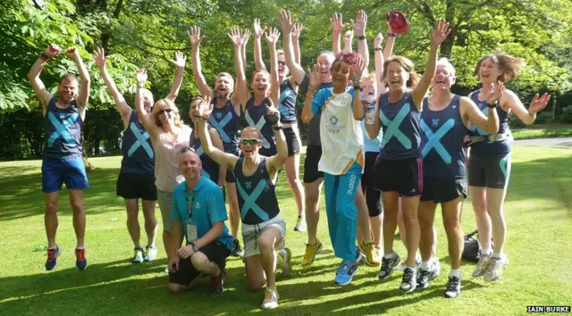 Baton bearer Erica Christie poses with athletes, all with their hands in the air