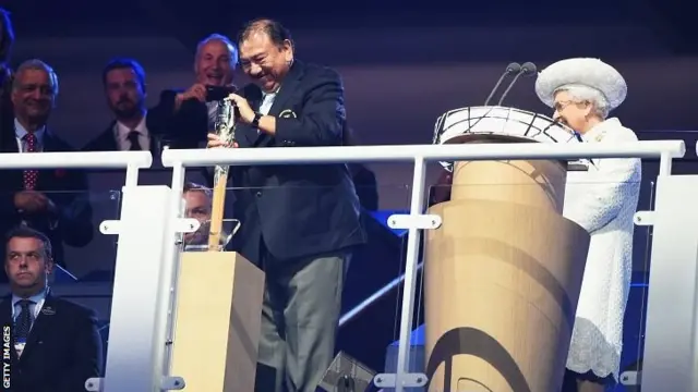 Prince Imran the CGF President attempts to retrieve the message from the baton as he presents it to Queen