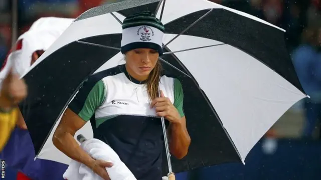 Zoe Brown of Northern Ireland shelters under an umbrella in the rain before the start of the women's pole vault final