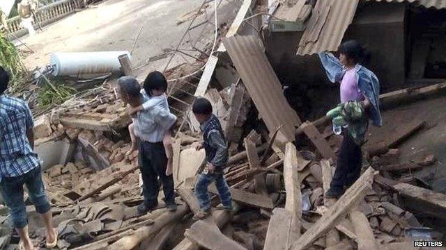 People walk among debris after an earthquake hit Ludian county, Yunnan province