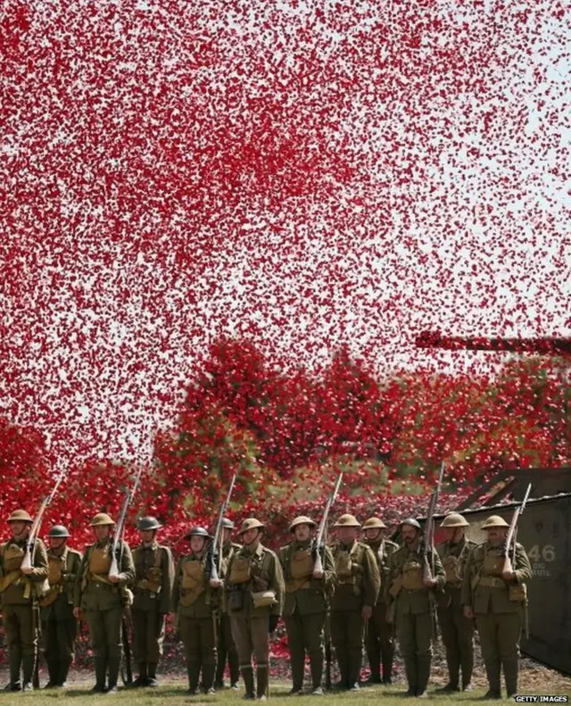 Members of the Great War Society stand under a shower of a million poppy flowers at the Tank Museum, Bovington, England