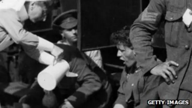 A nurse serves tea to wounded British soldiers