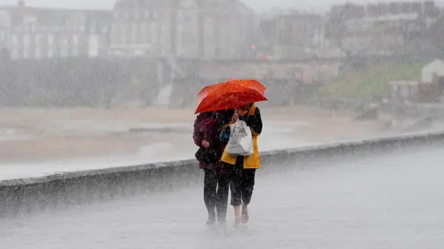 Two people struggling in the heavy rain