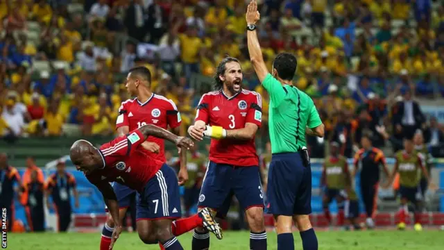 Colombia players surround Carlos Velasco Carballo