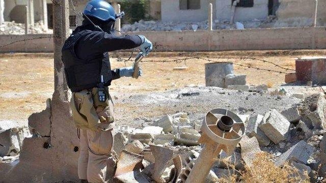 UN investigator takes samples of sands near a part of a missile likely to be one of the chemical rockets used by the regime in August 2013