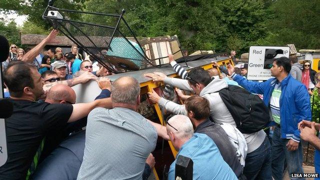 People at the adventure park try to get the tipped train back on its wheels