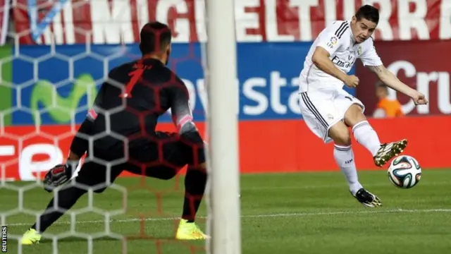 Real Madrid's James Rodriguez kicks the ball past Atletico Madrid's goalkeeper Miguel