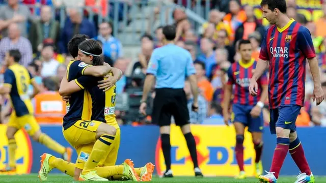 Barcelona's Lionel Messi looks on as Atletico Madrid's Juanfran and Filipe Luis celebrate