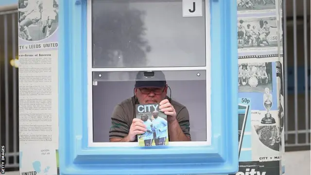 A programme seller shows off the matchday edition