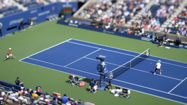 An image made with a tilt-shift lens showing Novak Djokovic of Serbia hitting a return to Kei Nishikori