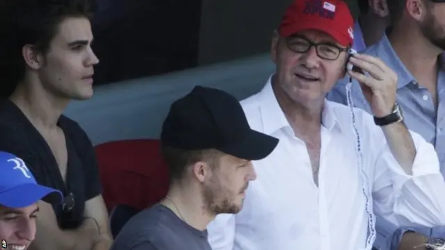 Actor Kevin Spacey, right, watches play between Kei Nishikori, of Japan, and Novak Djokovic