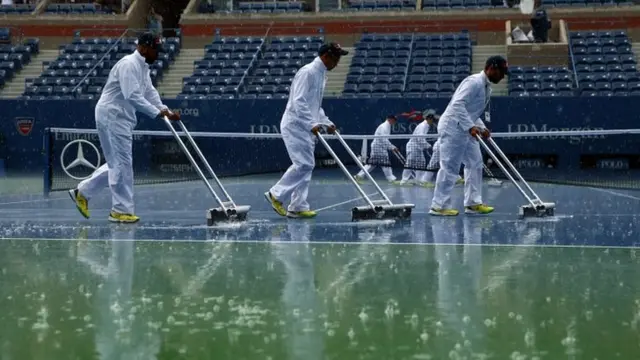 Grounds crew members attempt to dry the court