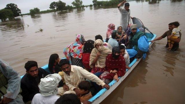 Pakistani rescue workers evacuate villagers from an area flooded by rain