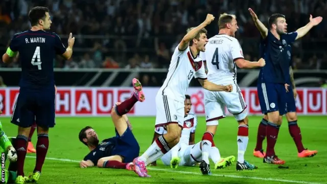 Scotland players react as Thomas Mueller of Germany celebrates