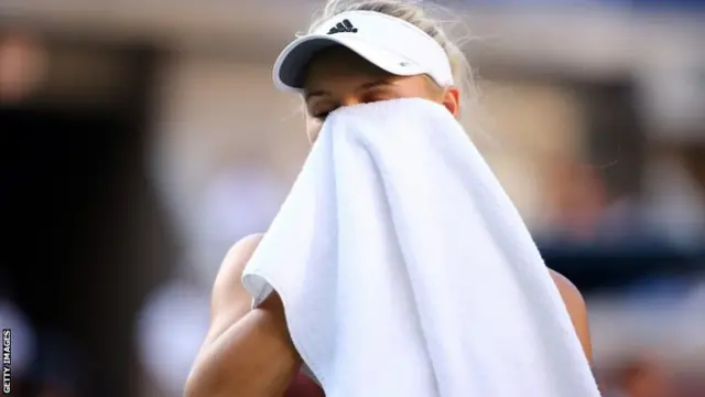 Caroline Wozniacki of Denmark wipes her face