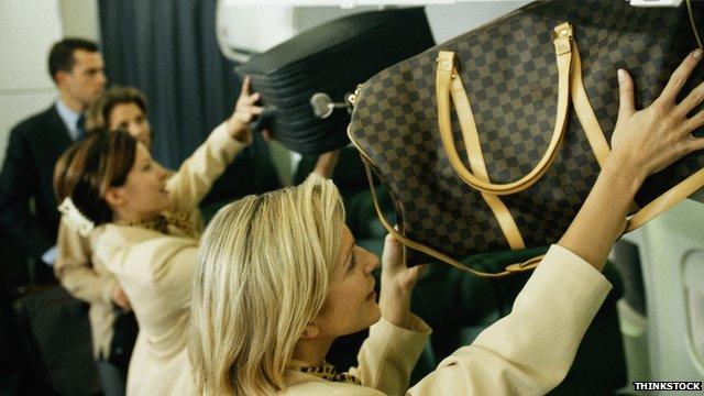 Passengers stow hand baggage on plane