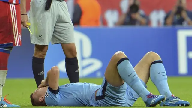 Manchester City's Edin Dzeko lies injured as he receives a yellow card