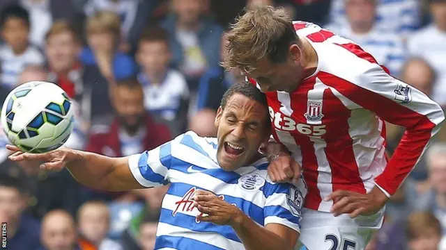 QPR's Rio Ferdinand and Stoke's Peter Crouch leap for the ball