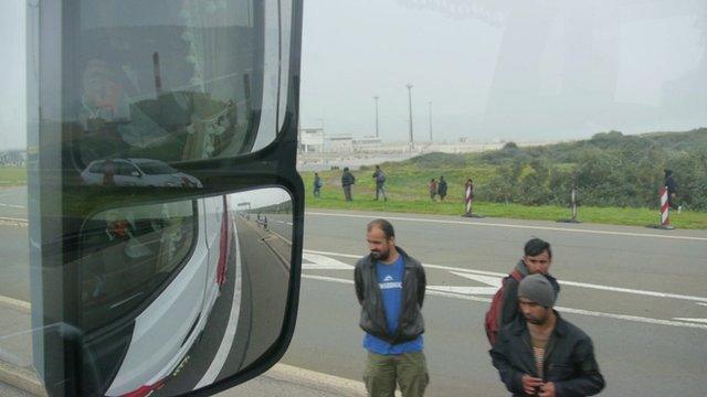 View from driver's window of migrants on road