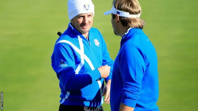 Graeme McDowell (L) talks to Victor Dubuisson of Europe