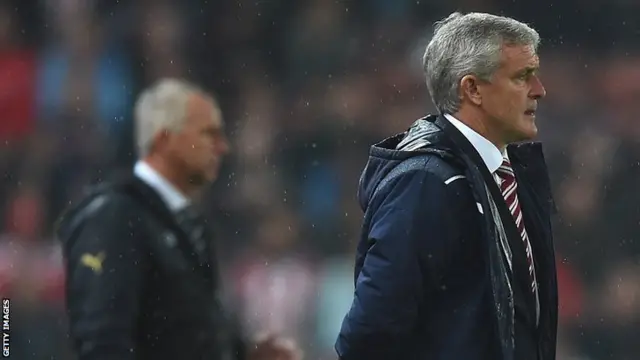 Stoke City manager Mark Hughes stands on the touchline with Newcastle boss Alan Pardew