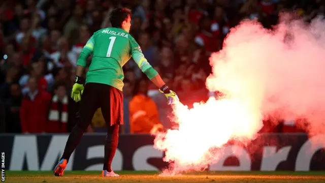 Fernando Muslera removes flares from the pitch