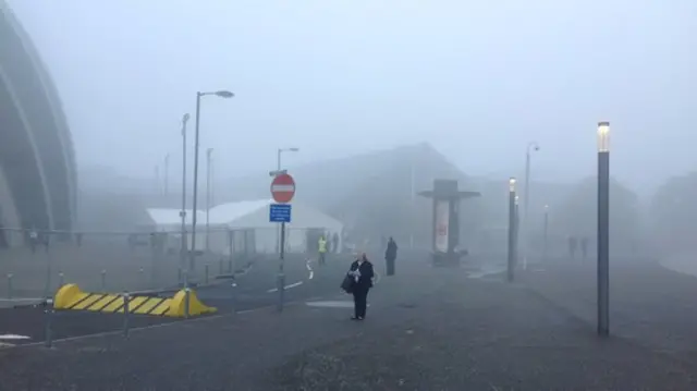 A women stands outside the Lib Dem conference venue in Glasgow on a misty morning