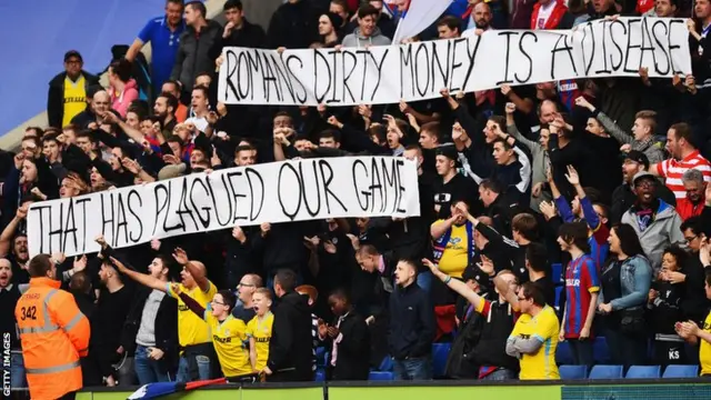 Crystal Palace fans display a banner reading: "Roman's dirty money is a disease that has plagued our game"