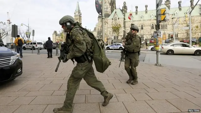 Armed police officers head towards Langevin Block on Parliament Hill following shooting. 22 Oct 2014