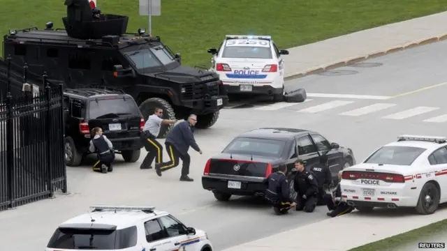 Police take cover outside parliament in Ottawa. 22 Oct 2014