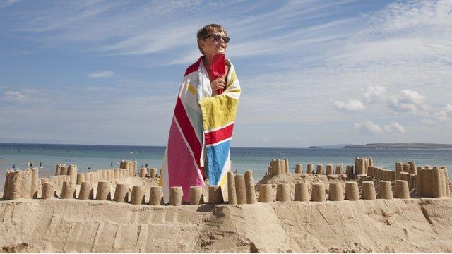 young boy on holiday building sandcastle