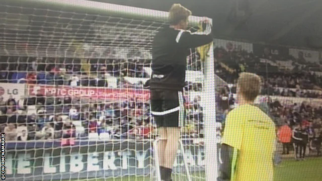 A referee measures a goal post