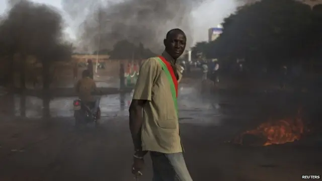 An anti-government protester wears a sash taken from the looted parliament building in Ouagadougou, capital of Burkina Faso, 31 October 2014.