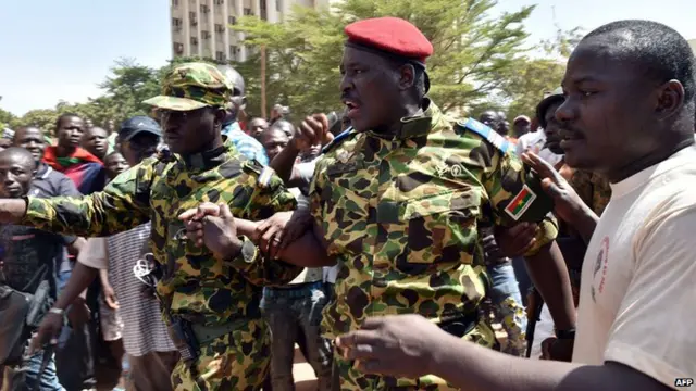 Burkinese Lieutenant-Colonel Issaac Zida (C) of the presidential guard leaves after reading a press release by the army chief after the resignation of Burkina Faso"s president in Ouagadougou on October 31, 2014