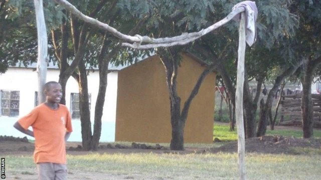 A young boy next to an improvised goal made from wood in Tanzania