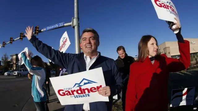 As viewed through fisheye lens, Cory Gardner, left, Republican candidate for the US Senate seat in Colorado, joins his wife, Jamie, and supporters in waving placards on corner of major intersection in south Denver suburb of Centennial, Colorado 4 November 2014