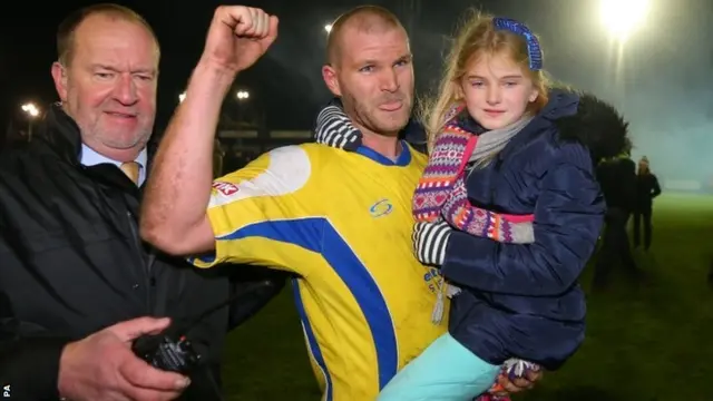 Craig Robinson, with his daughter in his his arms, celebrates at full-time