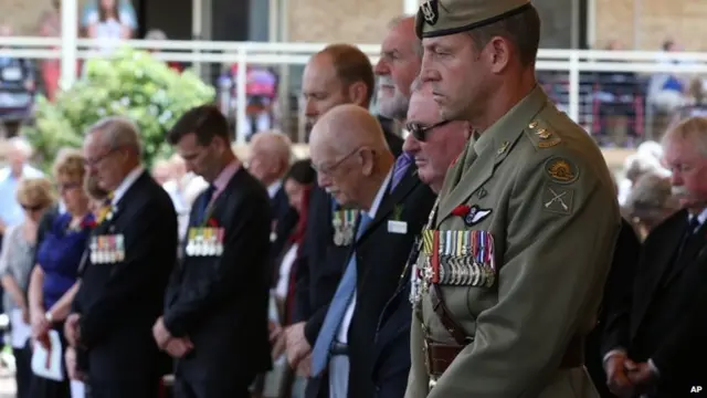 People bow their heads during a minute of silence at a Remembrance Day memorial service in Sydney, Australia