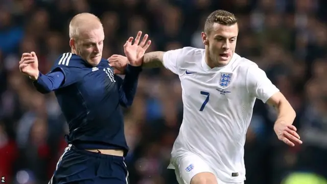 England midfielder Jack Wilshere holds off Steven Naismith