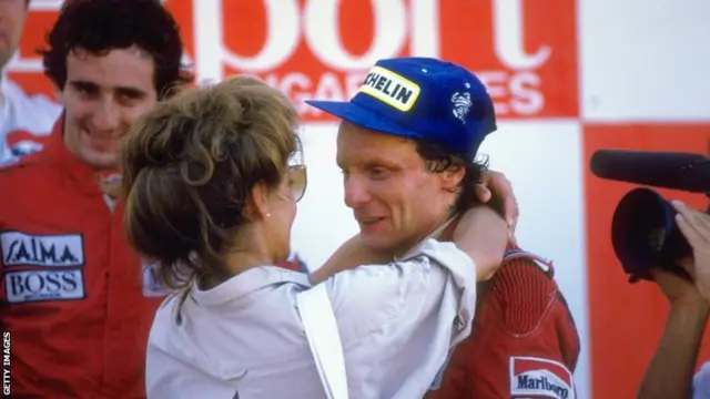 1984: McLaren TAG driver Niki Lauda (right) of Austria is congratulated by his wife watched by team mate Alain Prost (left) after the Portuguese Grand Prix at the Estoril circuit in Portugal