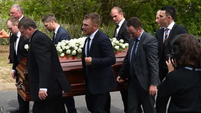 Pallbearers carry Hughes's casket