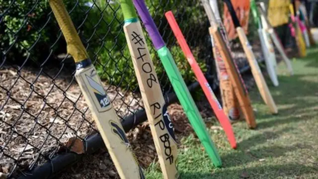 Cricket bats lean against the front fence of St Patrick's Primary School as a tribute to former student Hughes