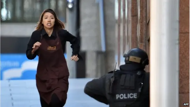 One of the hostages runs towards police from a cafe in the central business district of Sydney on 15 December 2014