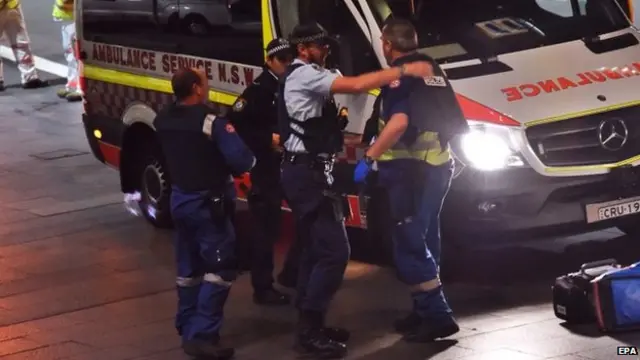 Police put body armour on ambulance personnel during the siege outside the cafe in Martin Place, Sydney (16 October 2014)