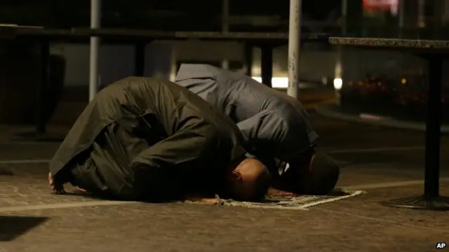 Two Muslim men perform prayers after the cafe siege in Sydney (16 December 2014)