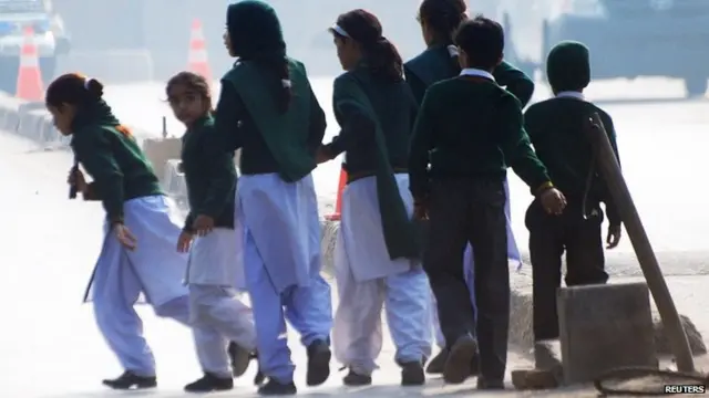 Schoolchildren cross a road as they move away from a military run school that is under attack by Taliban gunmen in Peshawar, 16 December 2014