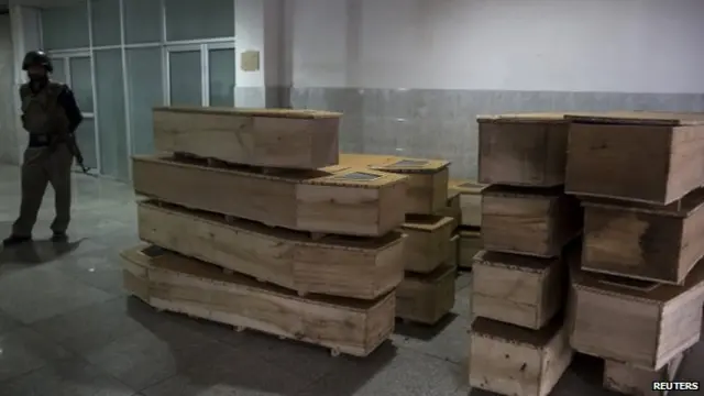 A policeman stands beside empty coffins at the hospital after the attack in Peshawar