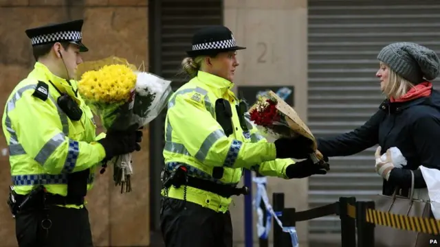 A member of the public delivers a floral tribute at the scene